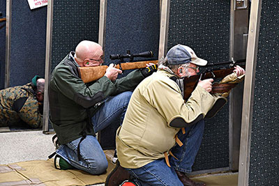 2 people shooting at an indoor range kneeling